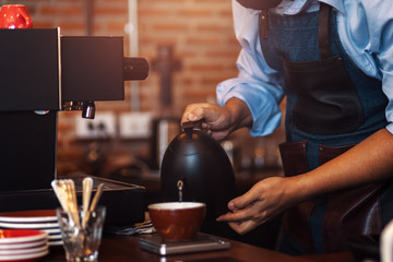 barista pouring boiling water from kettle to drip coffee maker.