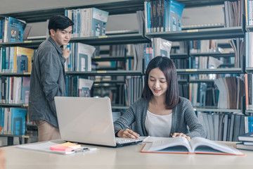 High school or college students studying and reading together in library. Student use laptop at library.