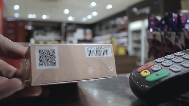 Seller near the checkout serves the client by reading the barcode with a laser.