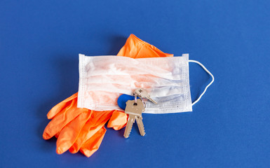 medical mask and gloves lie with keys on a background of blue color