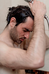 Obraz premium Handsome young single male washing his body and face in bathroom.