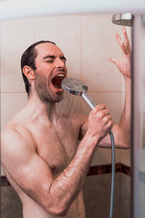 Handsome young single male washing his body and face in bathroom.