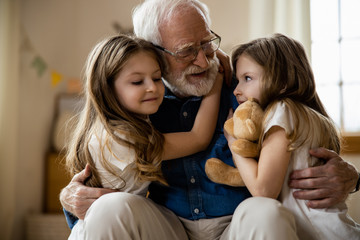 Mirthful children hugging their grandpa stock photo
