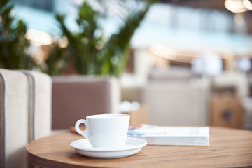 Cup of coffee and book on wooden table