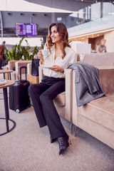 Attractive young woman drinking coffee in departure lounge