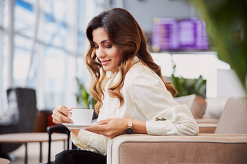 Charming young woman holding cup of coffee