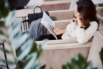 Charming young woman reading book in departure lounge