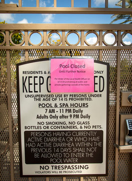 Coronavirus Pandemic related sign at common area pool stating pool closed until further notice on a sunny day. The sign also states people should stay home and not gather together