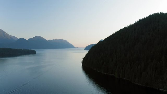 Drone flying out over beautiful lake during sunset 