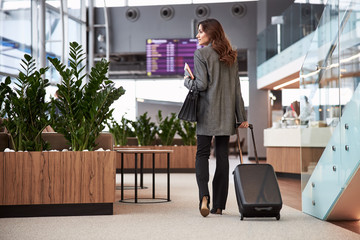 Charming lady with trolley bag walking in departure lounge