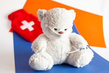 teddy bear in a medical mask with an electronic thermometer in his pawon a classic blue and lush lava background color