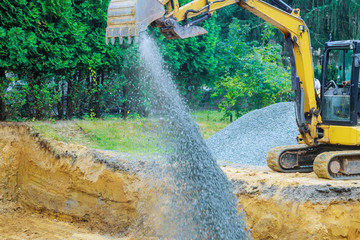 Working on a construction excavator moving gravel stones for foundation building