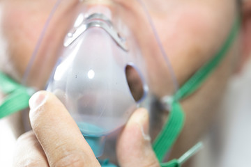 The bearded man has an oxygen mask on his face. Close-up. The patient has trouble breathing. Close up.