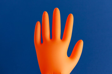 Inflated orange rubber glove isolated on blue background
