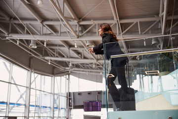 Stylish lady standing on second floor of airport waiting zone