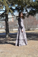 Молодая девушка в длинном платье гуляет в парке