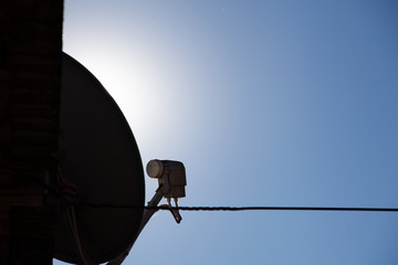 Antena parabólica em perfil com céu no fundo