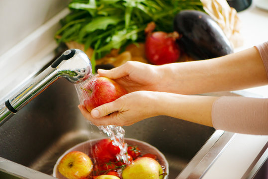 Washing fruit in the kitchen, white hands