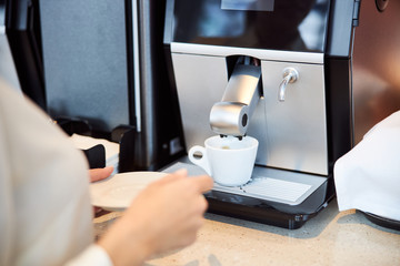 Young woman is using automatic coffee machine