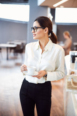 Attractive young woman holding cup of coffee