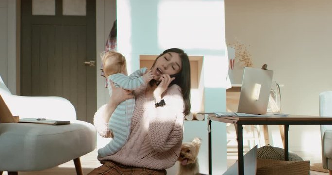 Young mother working from home surrounded by daughter and dog, having a work call. Stay home, quarantine remote work. Shot on RED Dragon