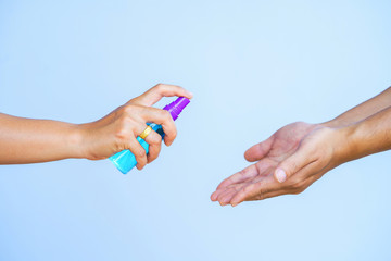 Woman spray alcohol to wash hands protect Covid-19 isolated on blue background.