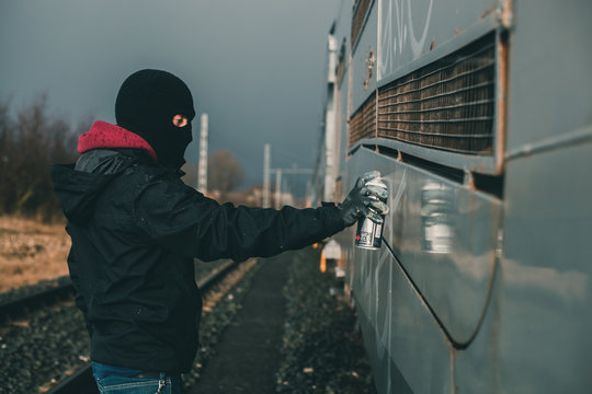 Graffitero realizando pintada sobre un vagón dede mercancías