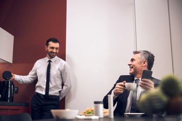 Happy office workers talking to each other in the kitchen