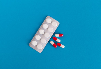 red-white pills and tablets in a blister pack on a blue background
