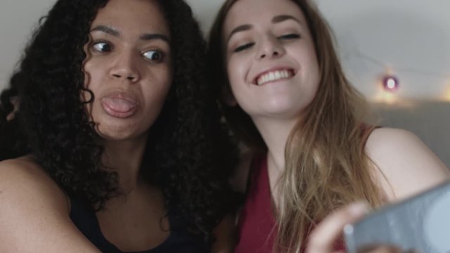 Female friends taking selfie in bedroom