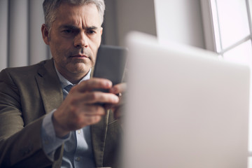 Caucasian man is typing on smartphone in office