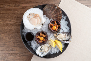 Top view of seafood platter: shellfish, oysters, sea urchin and balsamic sauce