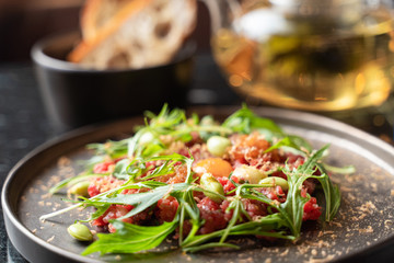 Beef tartare with egg yolk and kale salad in a fancy restaurant