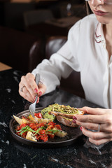 Eating raw meat tartare with fork, woman hands is in the shot