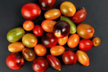 Fresh ripe mixed tomato verity assorted color on black background