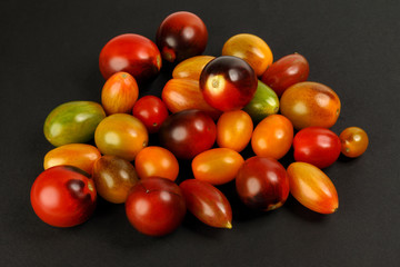 Fresh ripe mixed tomato verity assorted color on black background