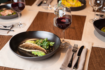 Roasted sea bass with parsley and avocado on a black plate, served as a part of romantic dinner in a restaurant