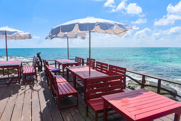 Fototapeta na wymiar Terrace view sea with wooden table and chairs on the beach landscape nature with sunlight on umbrella - wooden balcony view seascape idyllic seashore restaurant by sea in the resort