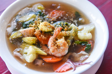 Thick Gravy seafood noodles with squid shrimp prawn and vegetable on bowl on wooden table background -