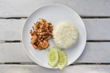 Garlic Fried Seafood / Fried shrimp squid fish with rice on white plate and cucumber