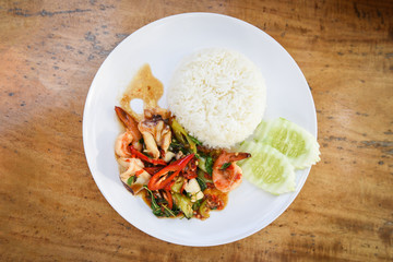 Stir fried seafood squid shrimp prawn with holy basil and rice / Thai food spicy fried recipe with cucumber and chili