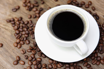 Coffee cup and coffee beans on table / black coffee in white mug on wooden background