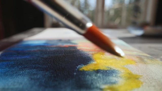 Artist painting with watercolor paint, closeup on brush