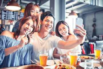happy young people sitting in  restaurant and taking  selfie