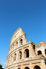 Naklejka premium The exterior facade of the Colosseum or Coliseum with the arches against blue clear sky in Rome, Italy