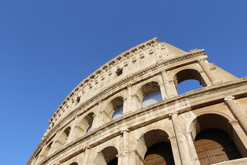 Obraz premium The exterior facade of the Colosseum or Coliseum with the arches against blue clear sky in Rome, Italy