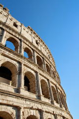 Fototapeta premium The exterior facade of the Colosseum or Coliseum with the arches against blue clear sky in Rome, Italy
