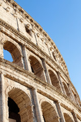 Fototapeta premium The exterior facade of the Colosseum or Coliseum with the arches against blue clear sky in Rome, Italy