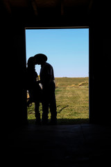 Silhouette of cowboy and cowgirl kissing 