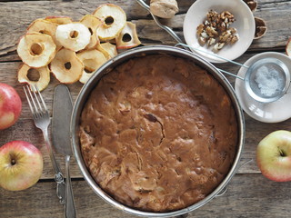 Round homemade fruit tart in a baking dish on a wooden ancient table with ingredients for sprinkling. Place for text.Top view.